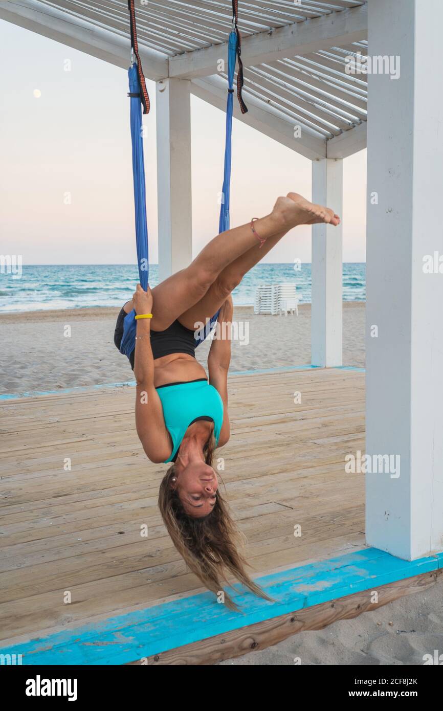 Donna rilassata che esegue lo yoga aereo appeso testa giù Foto Stock