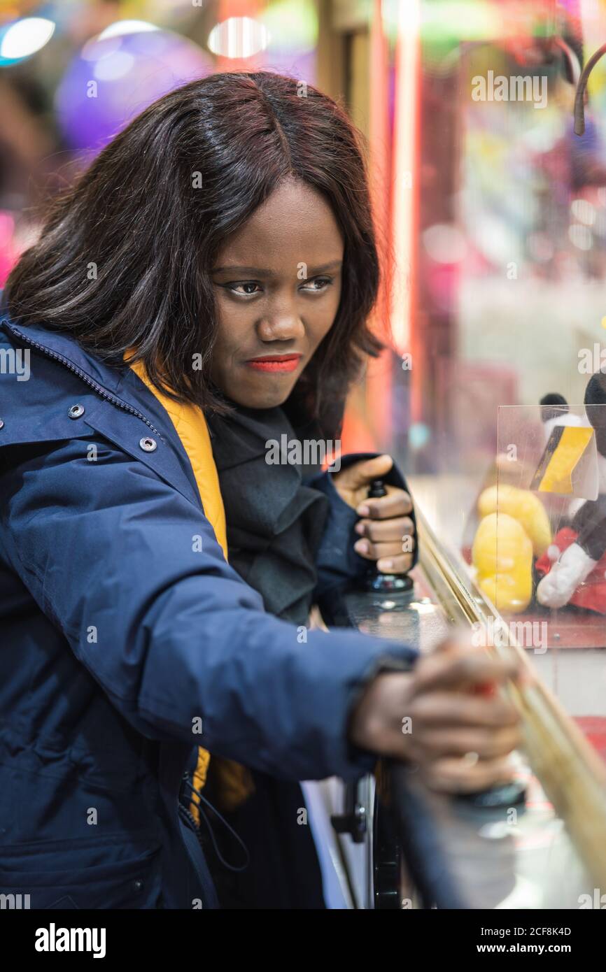 Donna nera che gioca a gru a artiglio Foto Stock