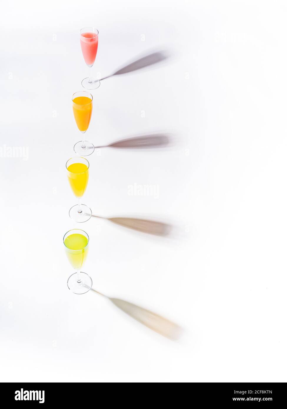 Ombre contrastanti da calici di giallo rosso arancio succoso e appetitoso bevande verdi su sfondo bianco Foto Stock