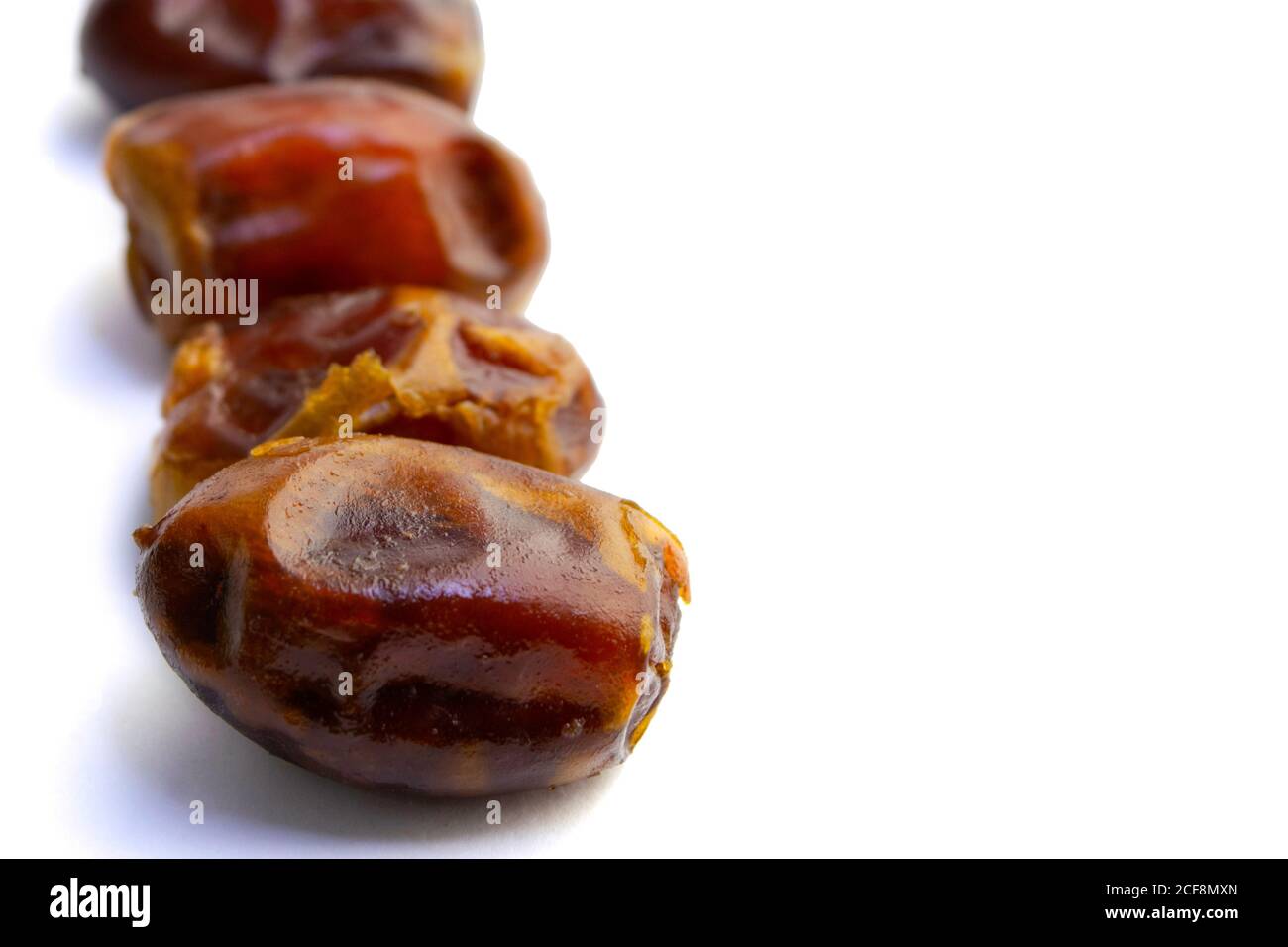 Dolci datteri asciutti disposti in fila, isolati su sfondo bianco. Copia paste Foto Stock