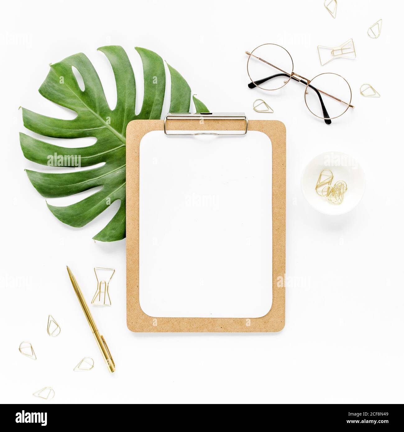 Home Office Workspace mockup con foglie tropicali Monstera, appunti, e accessori su sfondo bianco. Disposizione piatta, vista dall'alto Foto Stock