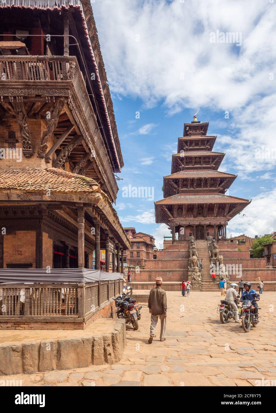 NEPAL, KATHMANDU - 4 AGOSTO 2014: Strada con le persone e gli edifici vicino a splendida torre alta con gradini Foto Stock