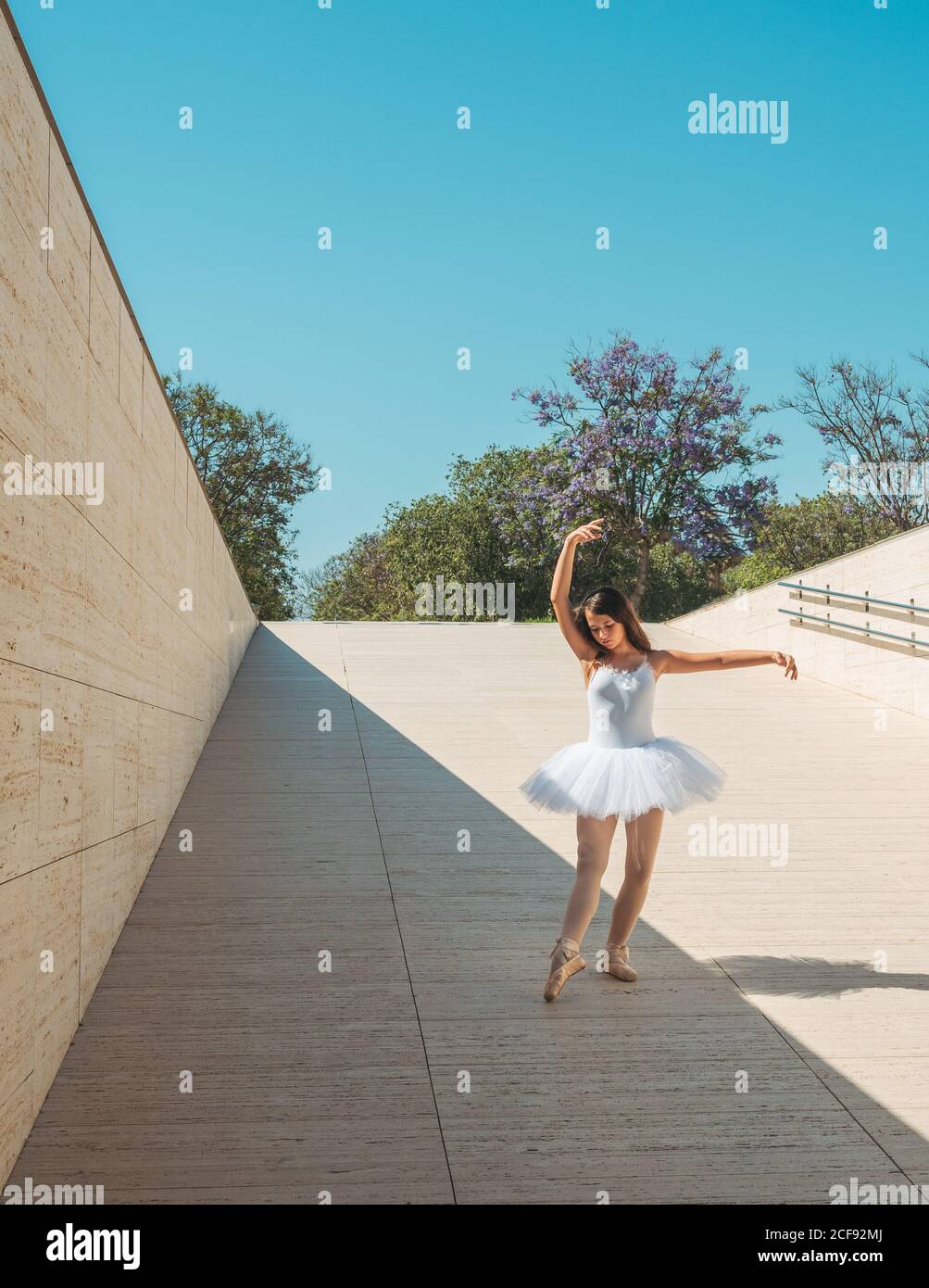 Classica posizione balletto con grazia eseguito da ballerina con mani alzanti e allungare le gambe all'esterno in una giornata di sole Foto Stock