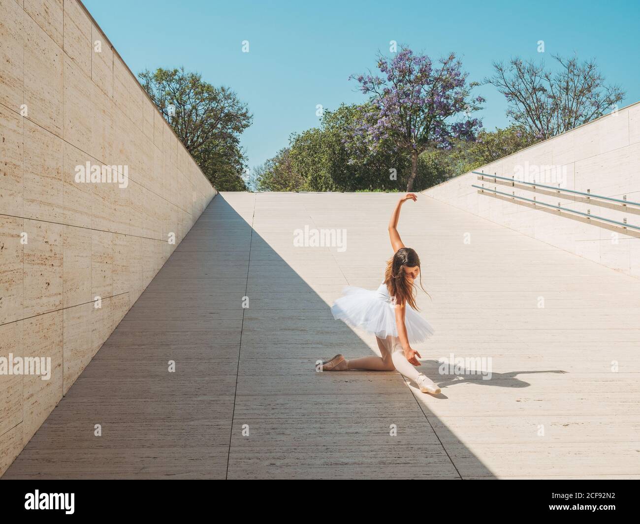 Classica posizione balletto con grazia eseguito da ballerina con mani alzanti e allungare le gambe all'esterno in una giornata di sole Foto Stock