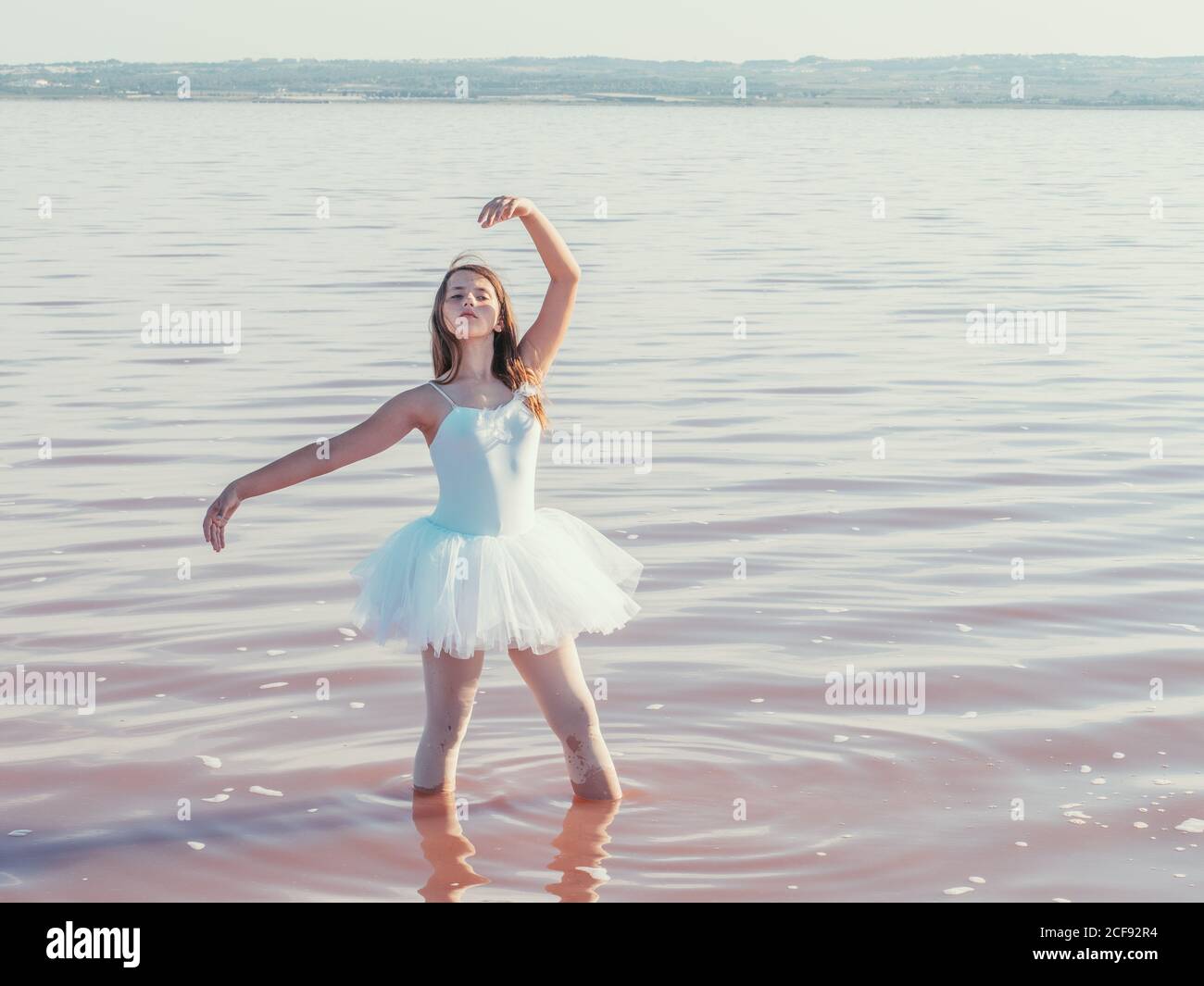 Classica posizione balletto con grazia eseguito da ballerina con mani alzanti in acqua fresca e ondulata in una giornata di sole Foto Stock