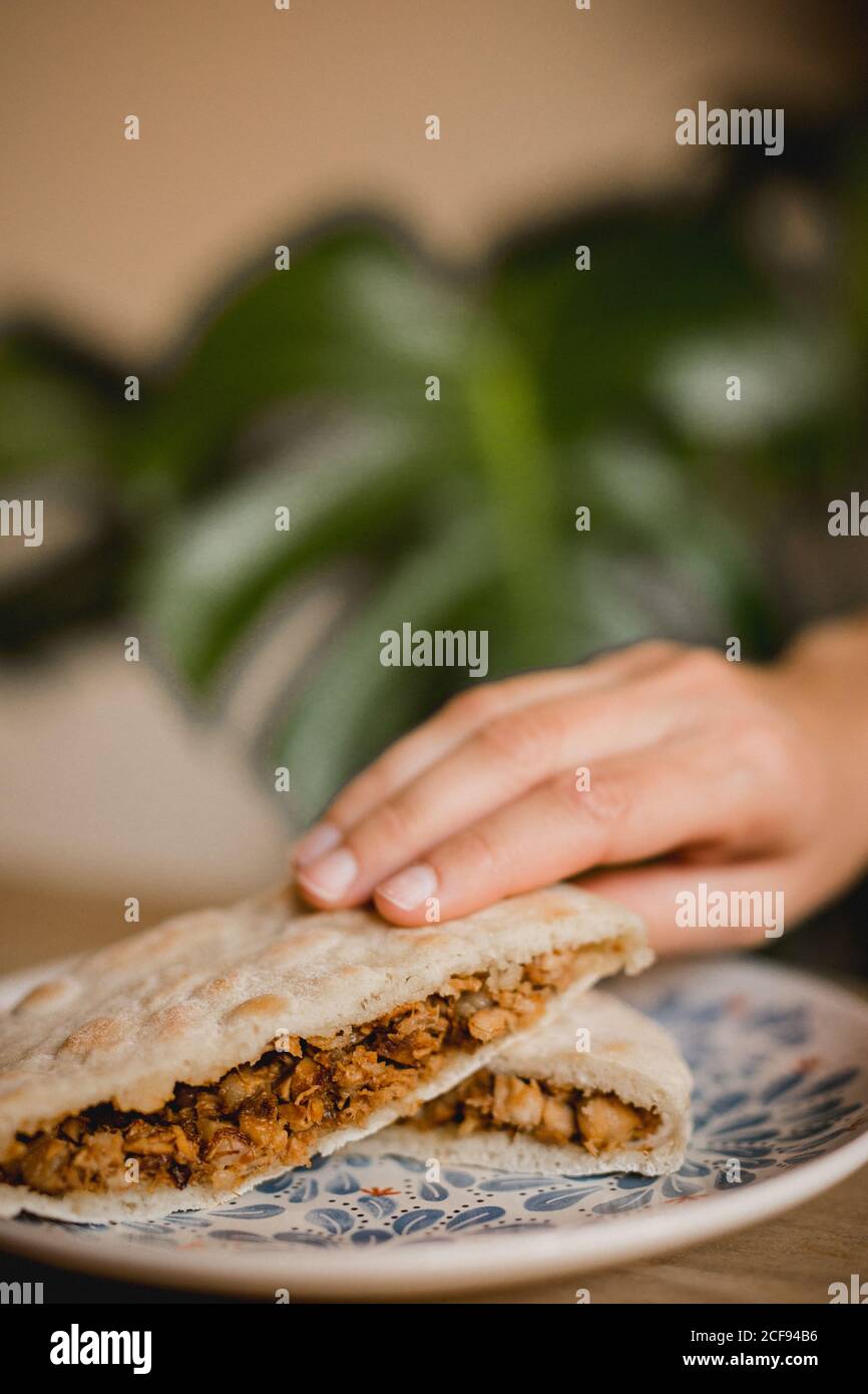 La tenuta a mano serviva appetitosi hamburger cinesi con maiale, anice stellato, cannella e panini caldi al vapore sul piatto nel caffè asiatico Foto Stock