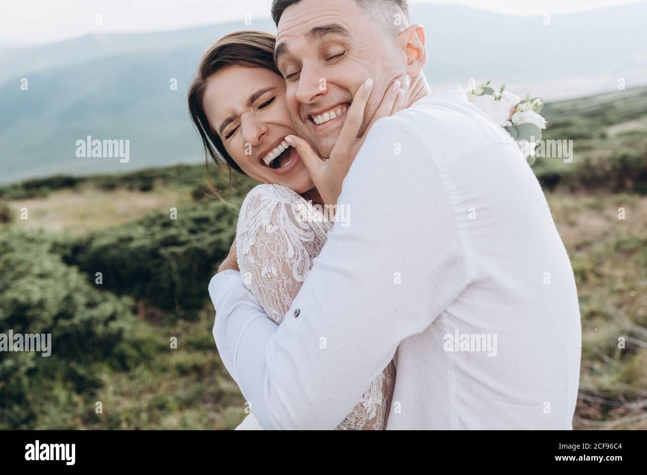 Felici sposi sorridenti, abbraccianti, che posano nei montani. Foto Stock
