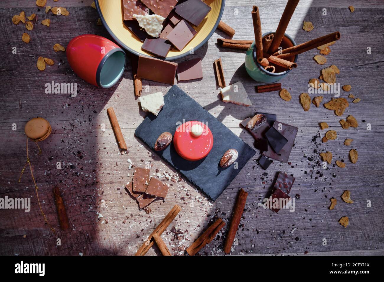 Dall'alto della tavola di ardesia con mousse di lamponi sul tavolo tra gli ingredienti disordinati con cioccolato e bastoncini di cannella Foto Stock