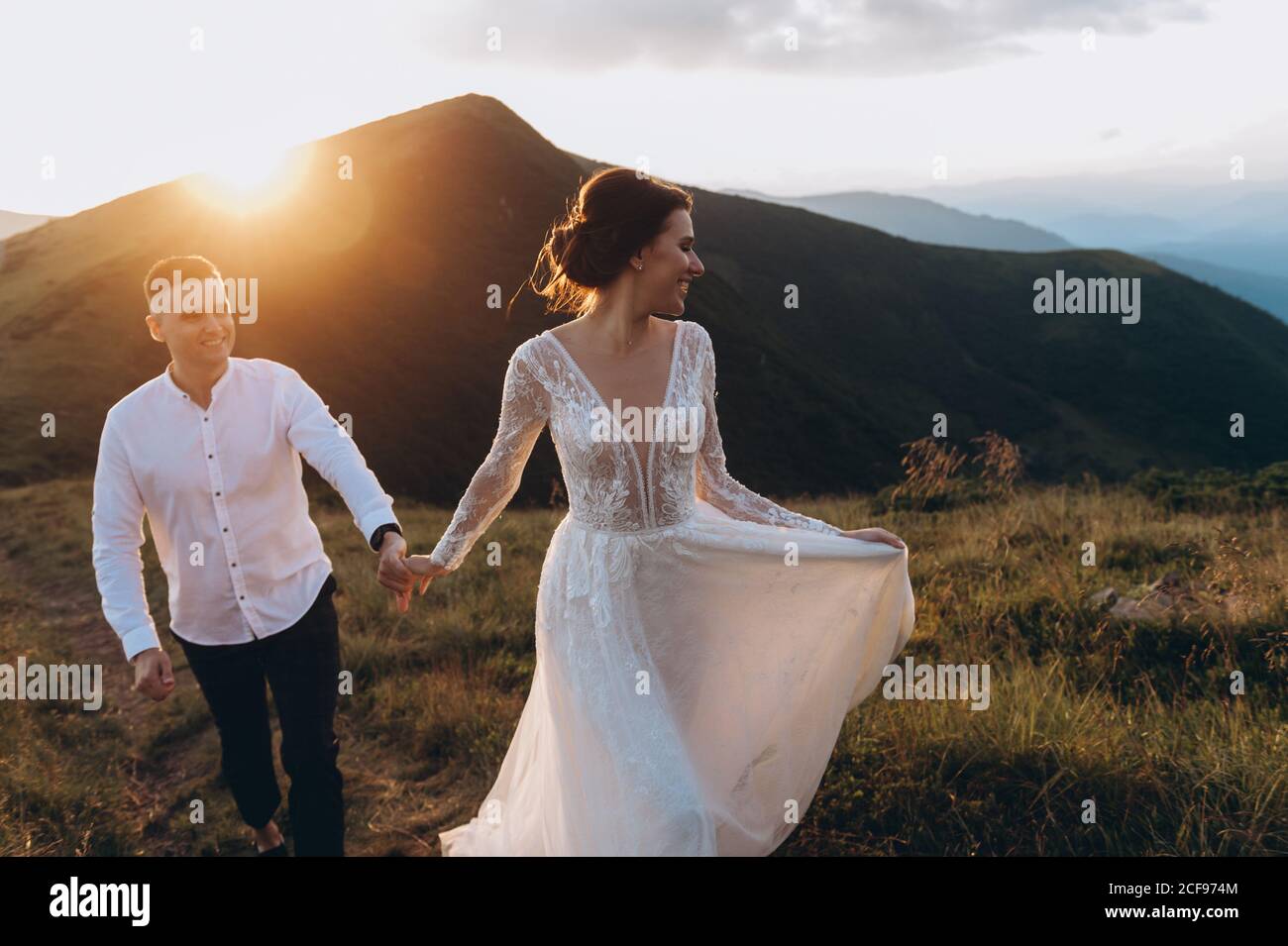 sposa e sposo in una passeggiata di nozze in montagna durante il tramonto. Foto Stock