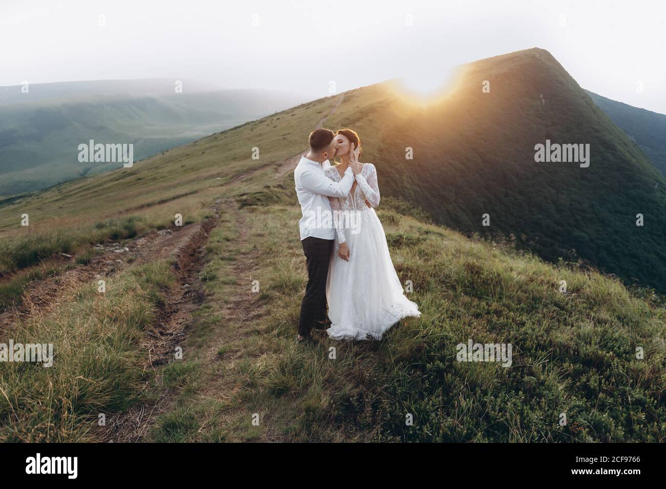 sposi novelli baciando in montagna. Matrimonio in montagna al tramonto. Foto Stock