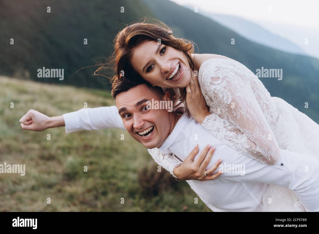 Sposi felici in pose divertenti sullo sfondo delle montagne. Foto Stock