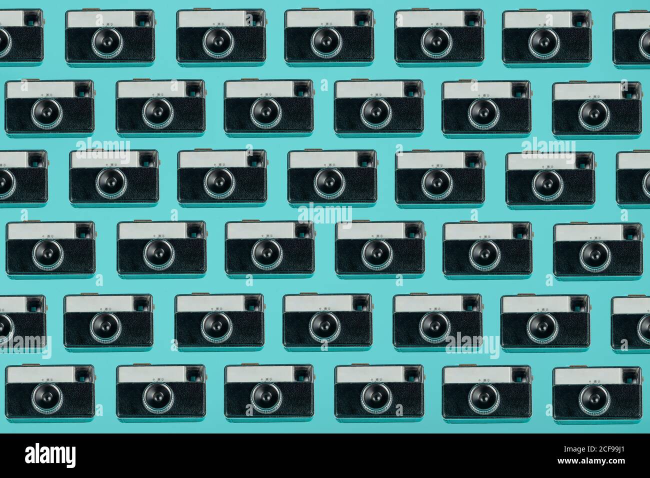 Modello senza cuciture composto da fotocamere vintage a soffitto disposte sopra sfondo blu Foto Stock