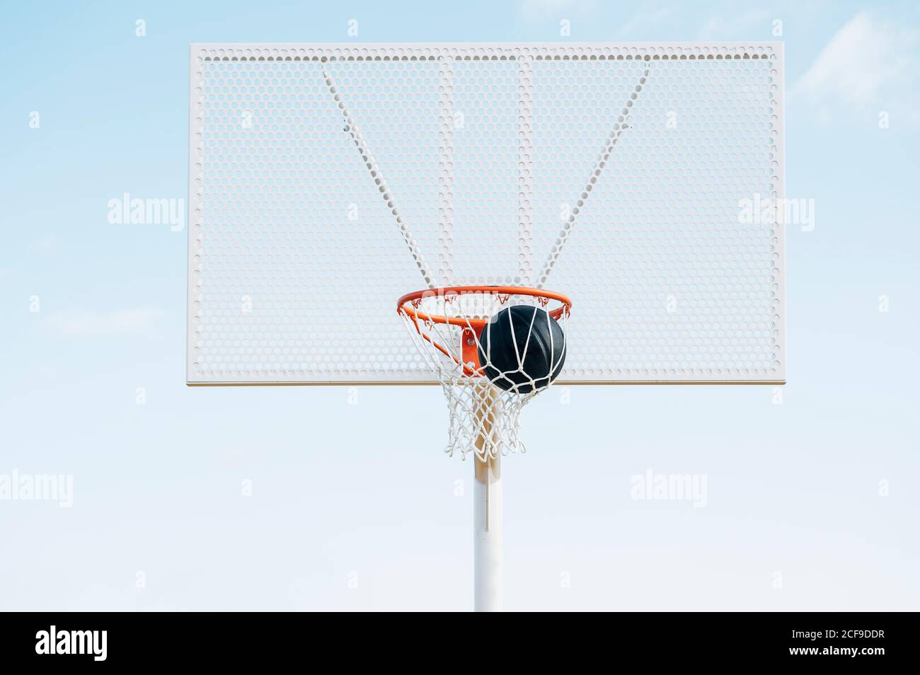 Palla nel cestino nel campo di pallacanestro all'aperto e palla nera Foto Stock