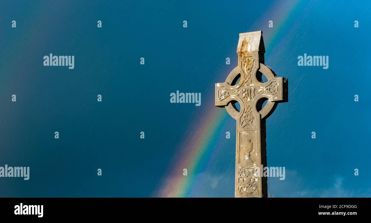 Arcobaleno sopra il vecchio cimitero irlandese della croce celtica Foto Stock