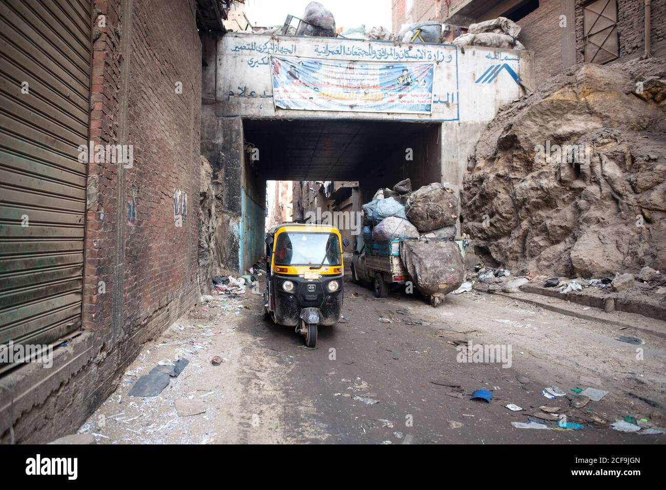 Cairo, Egitto - 14 dicembre 2019: Auto tuk tuk che scende su una strada vuota con rifiuti e edifici decaduti Foto Stock