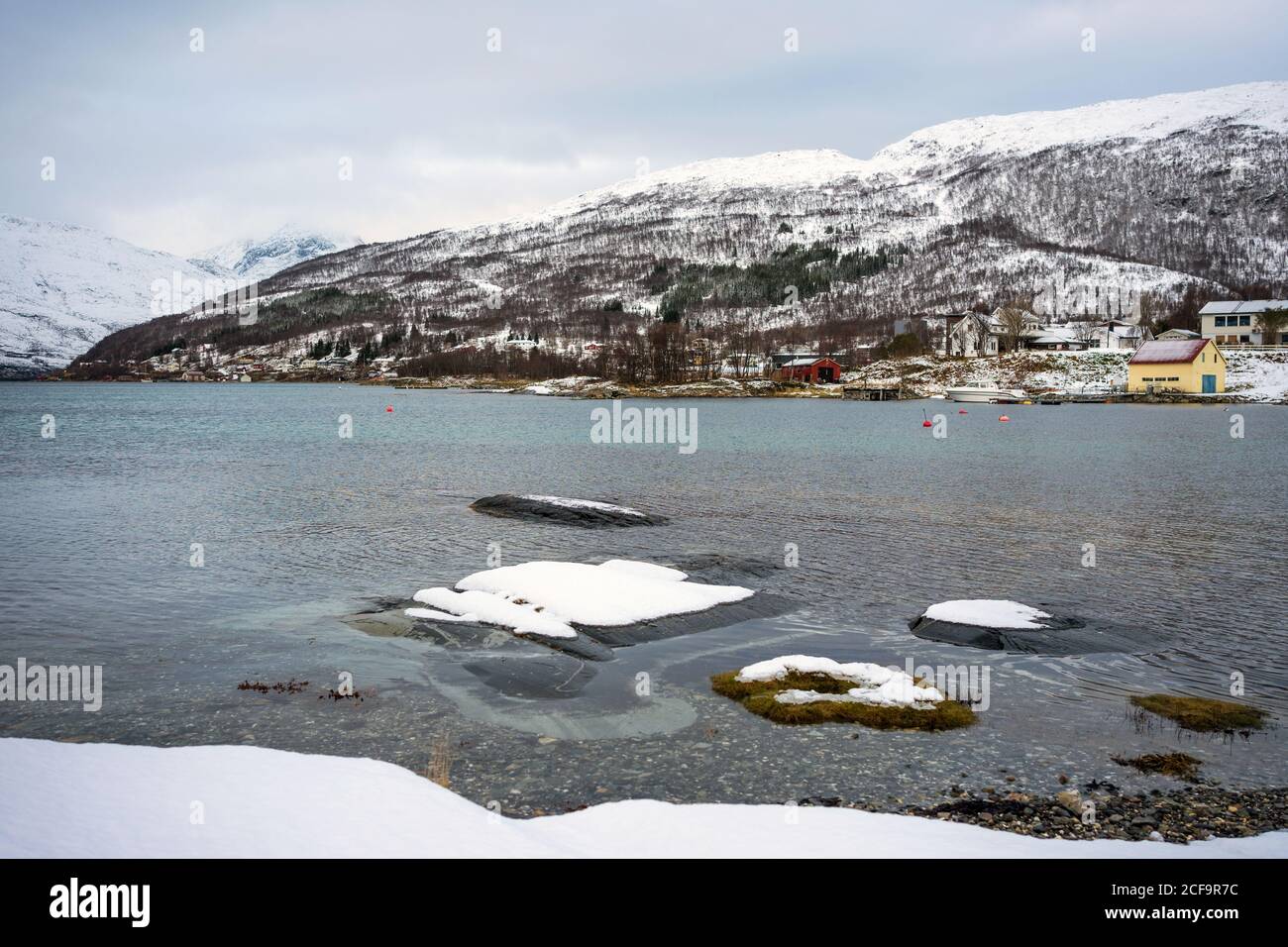 Bella natura nordica con mare e montagne innevate con piccole case sulla costa a Tromso, Norvegia Foto Stock