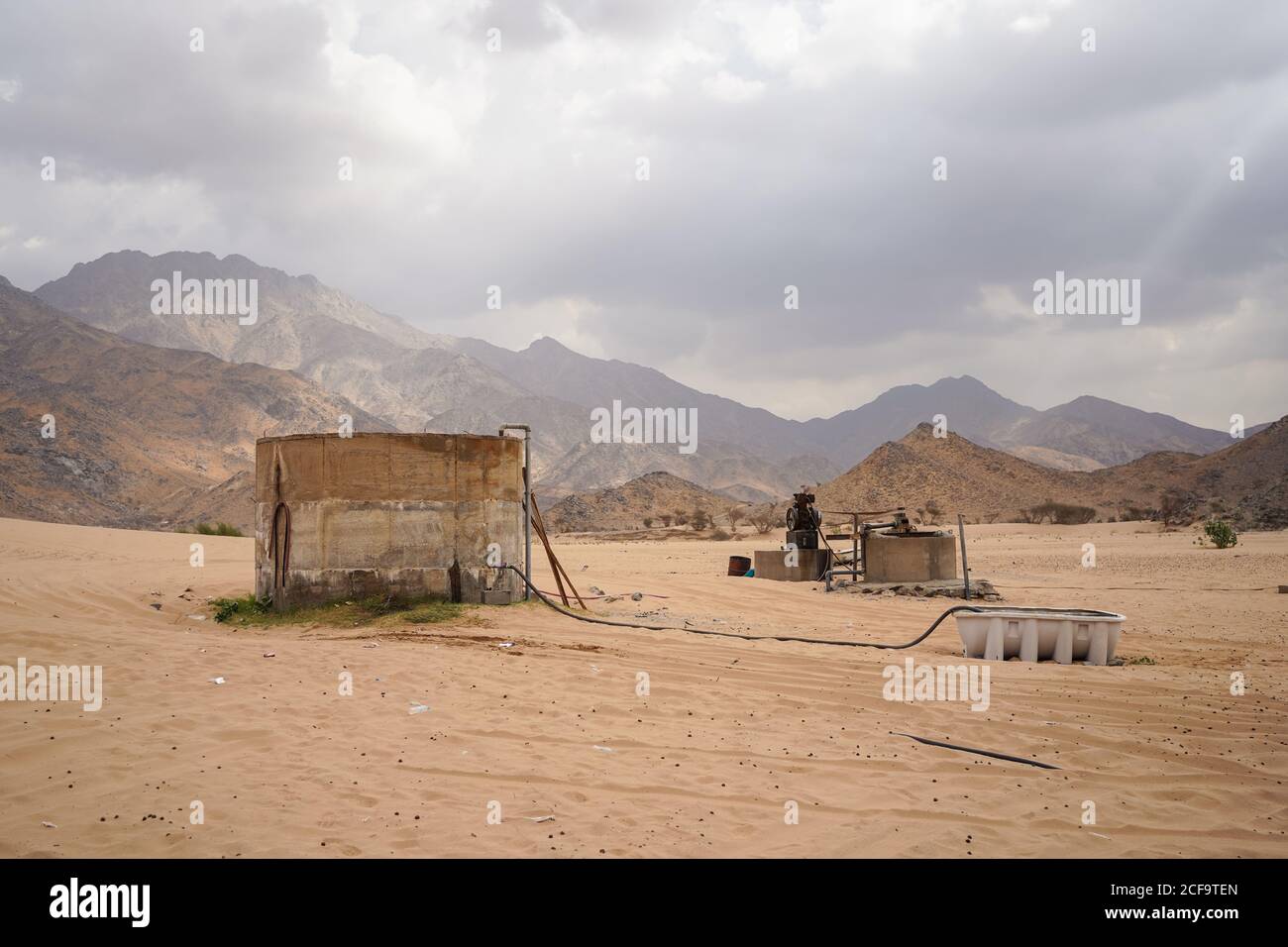 Terriccio acqua bene in posizione desertica vicino montagne in nuvoloso Giornata in Arabia Saudita Foto Stock