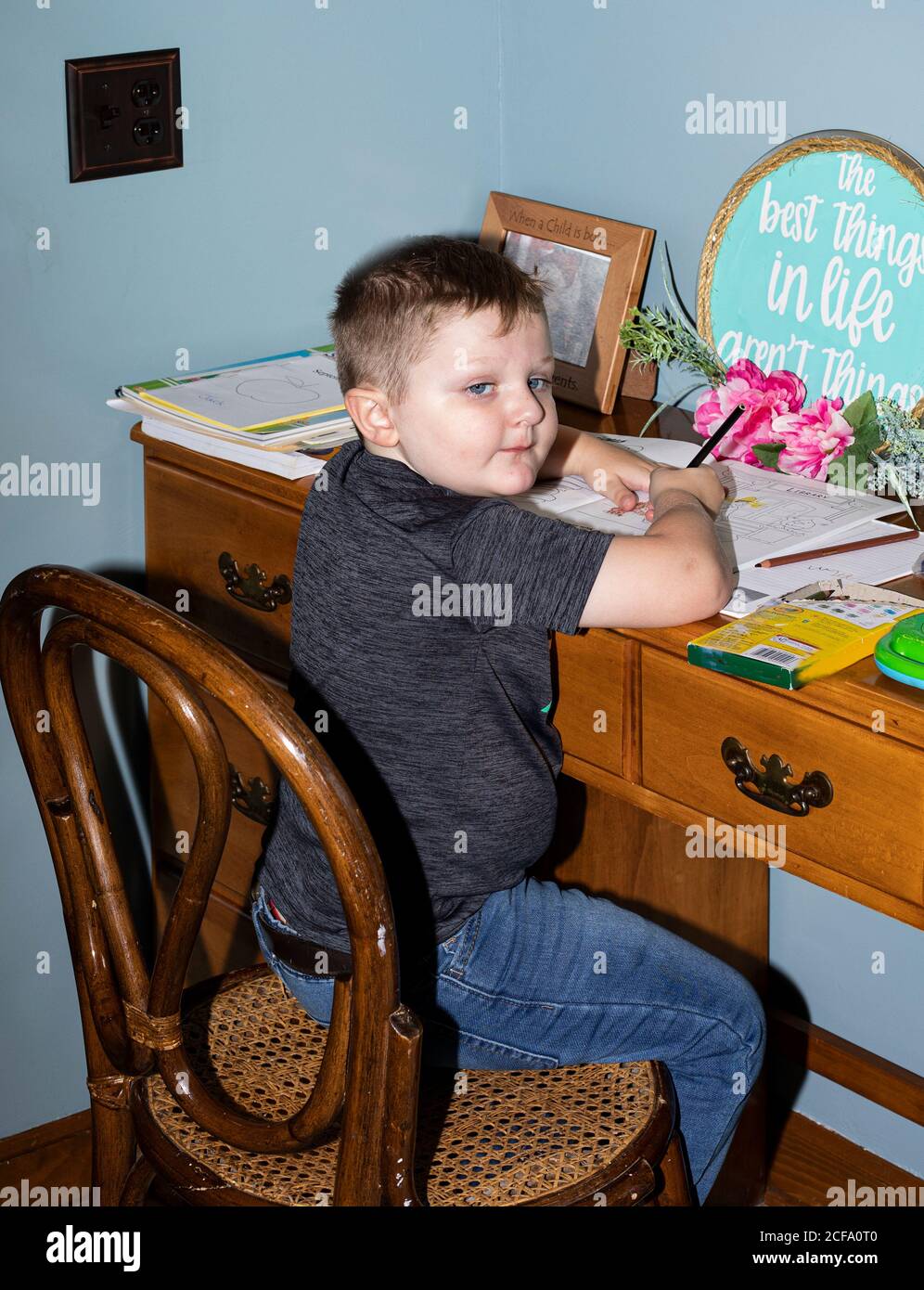 Il ragazzo di quattro anni lavora alla sua scrivania "scuola" a casa durante la sessione di lezione remota COVID-19. Foto Stock