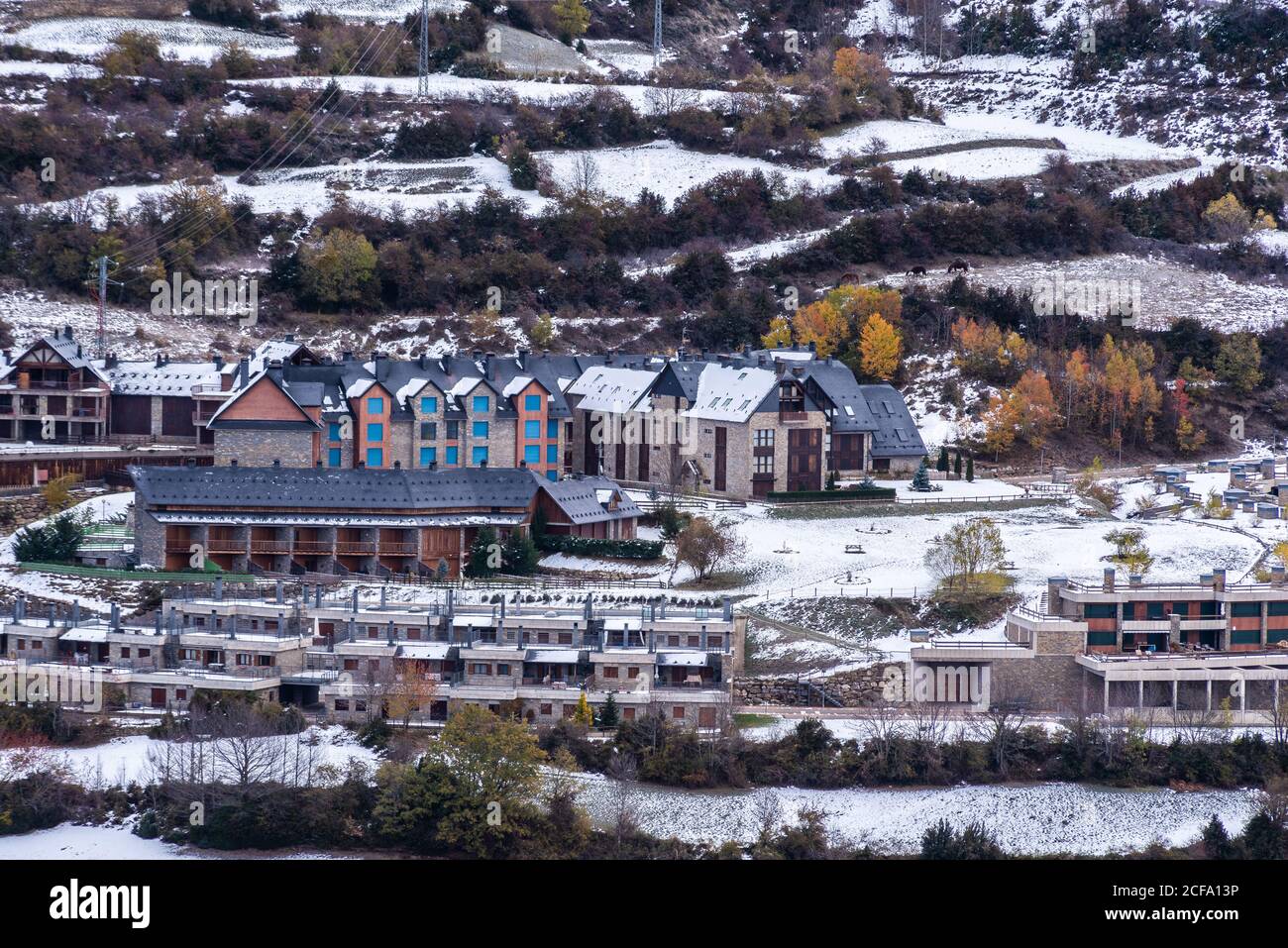 Drone vista di cottage e alberi d'autunno situato sulla neve collina pendio in città Foto Stock