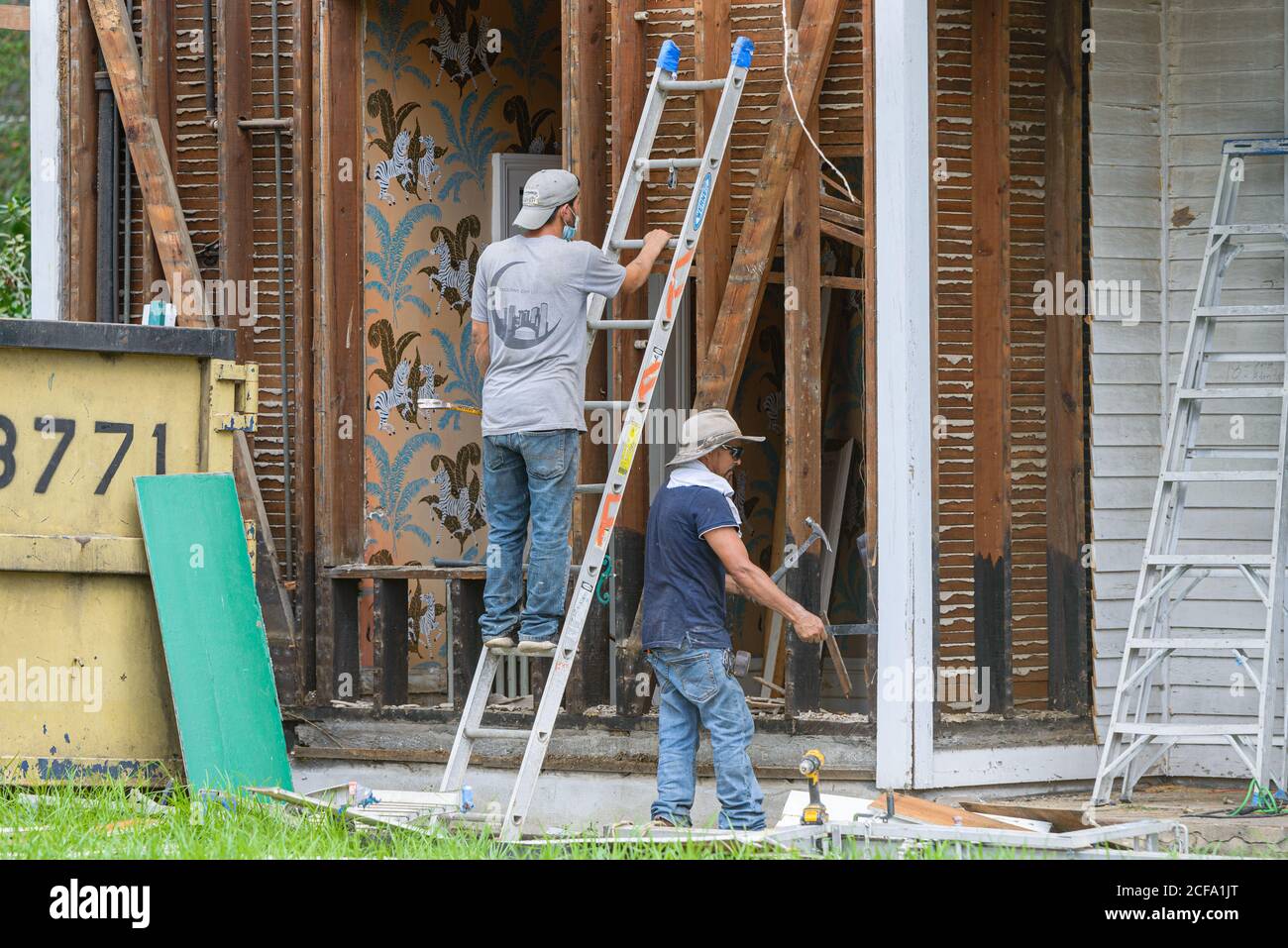 New Orleans, Louisiana/USA - 8/29/2020: Due lavoratori che si allontanano dalla vecchia casa con un lavoratore a scala Foto Stock