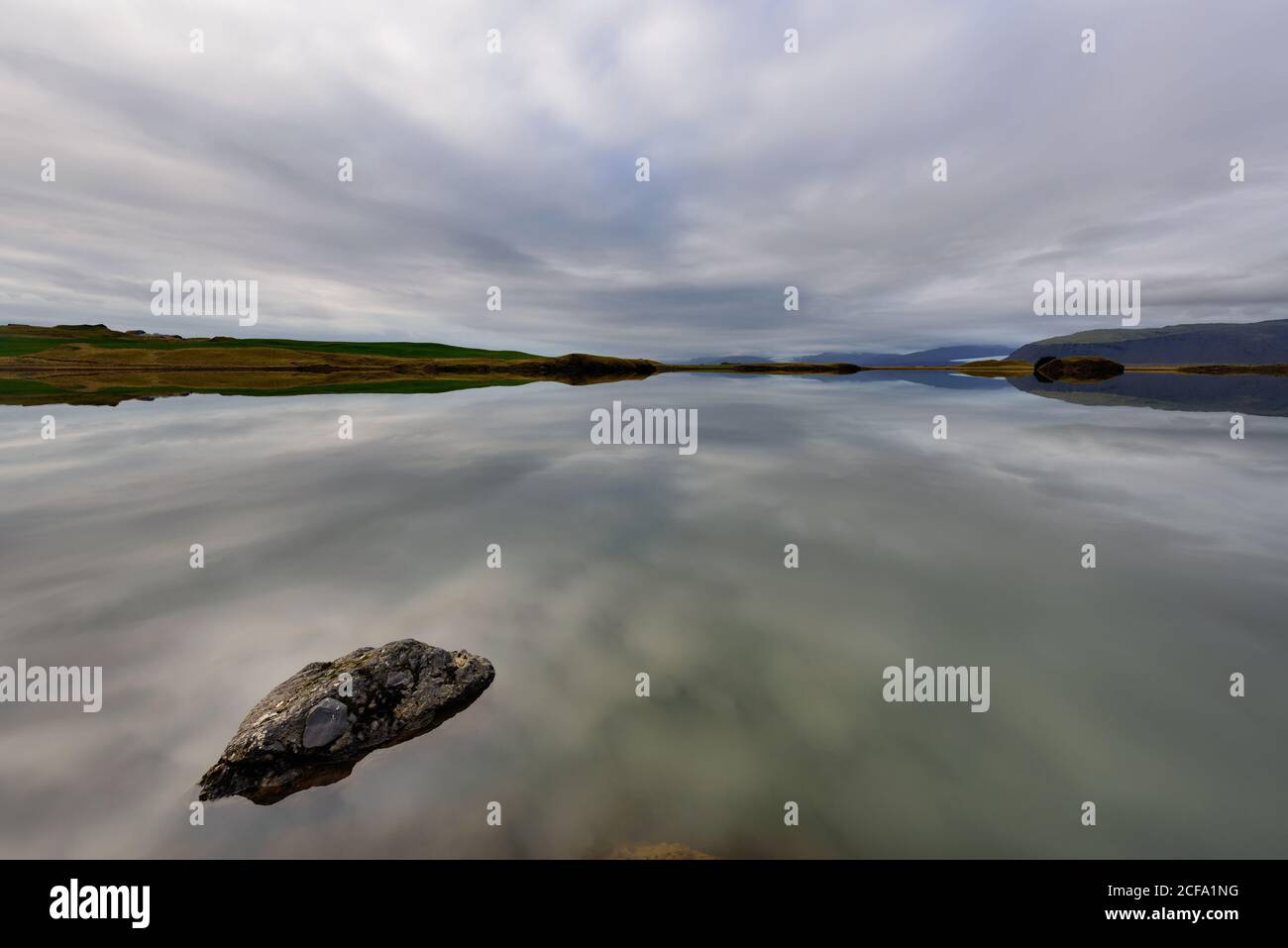 Paesaggio mozzafiato sul lago Thveit in Islanda. Meraviglia della natura con il cielo e la montagna riflessa in uno specchio d'acqua. Splendido backgro all'aperto Foto Stock