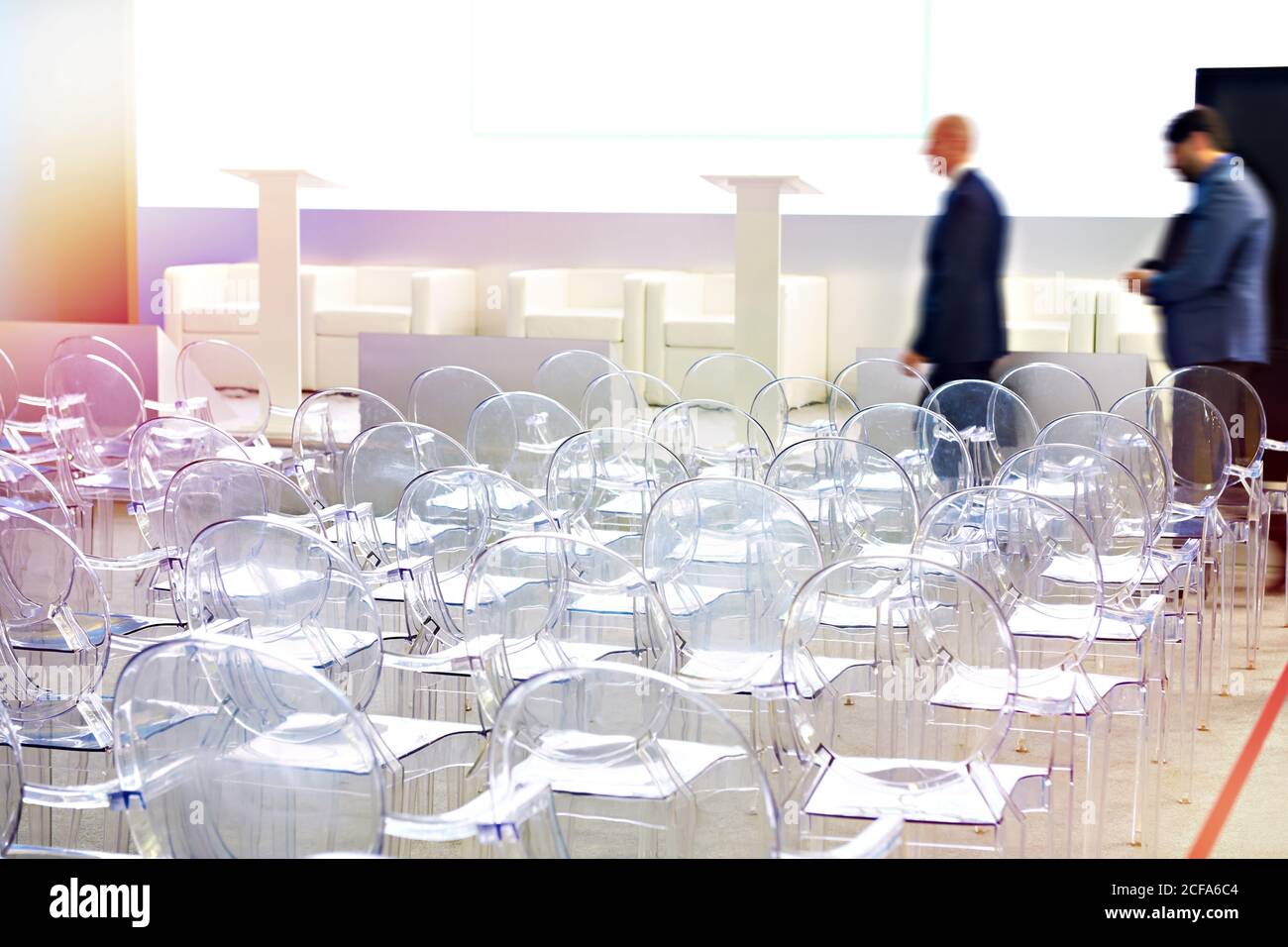 Sedie in plastica trasparente nella sala conferenze e persone Foto Stock