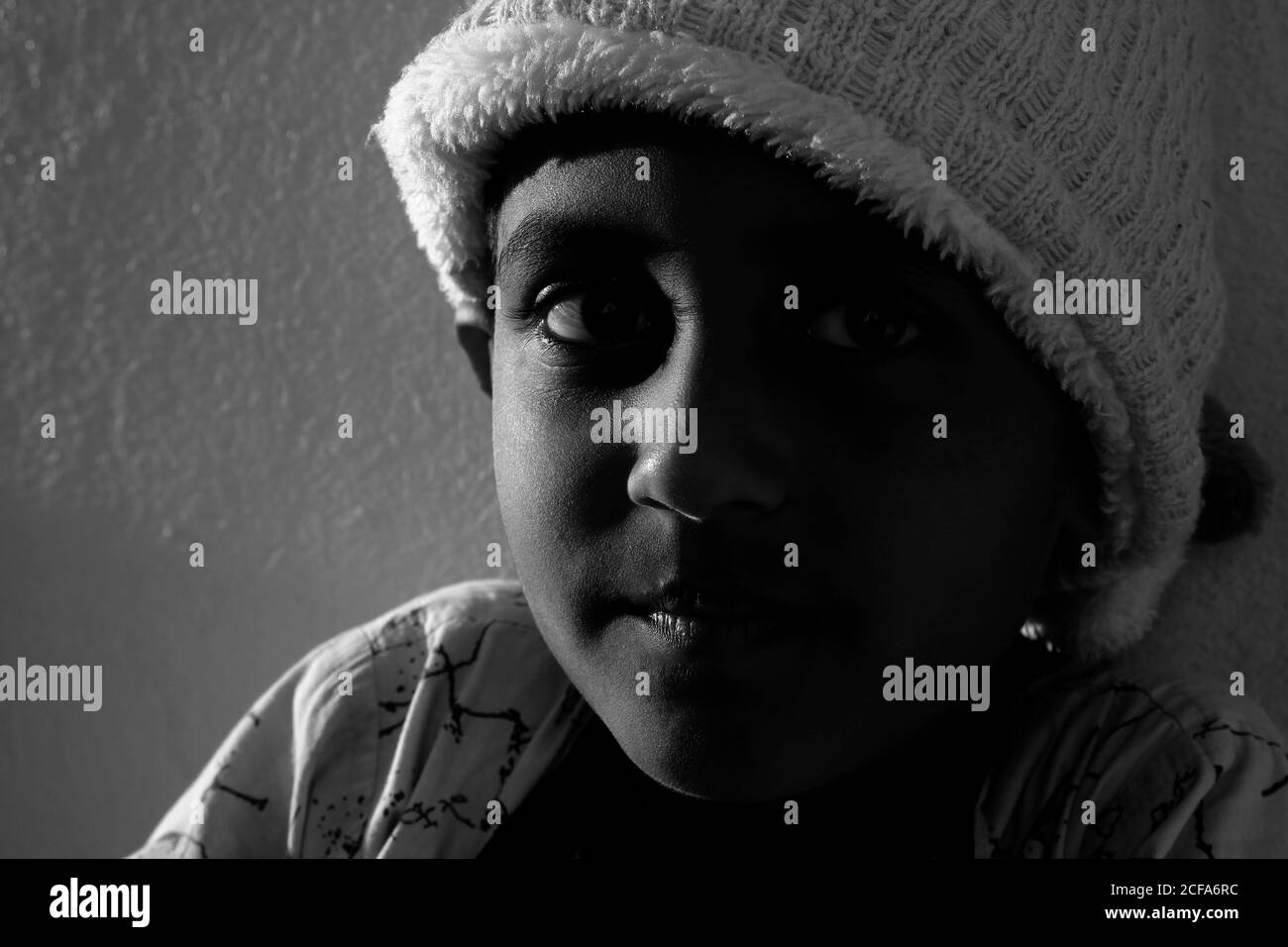 Un colpo closeup di ragazzo indiano con il cappuccio al tramonto foto in bianco e nero con illuminazione Foto Stock