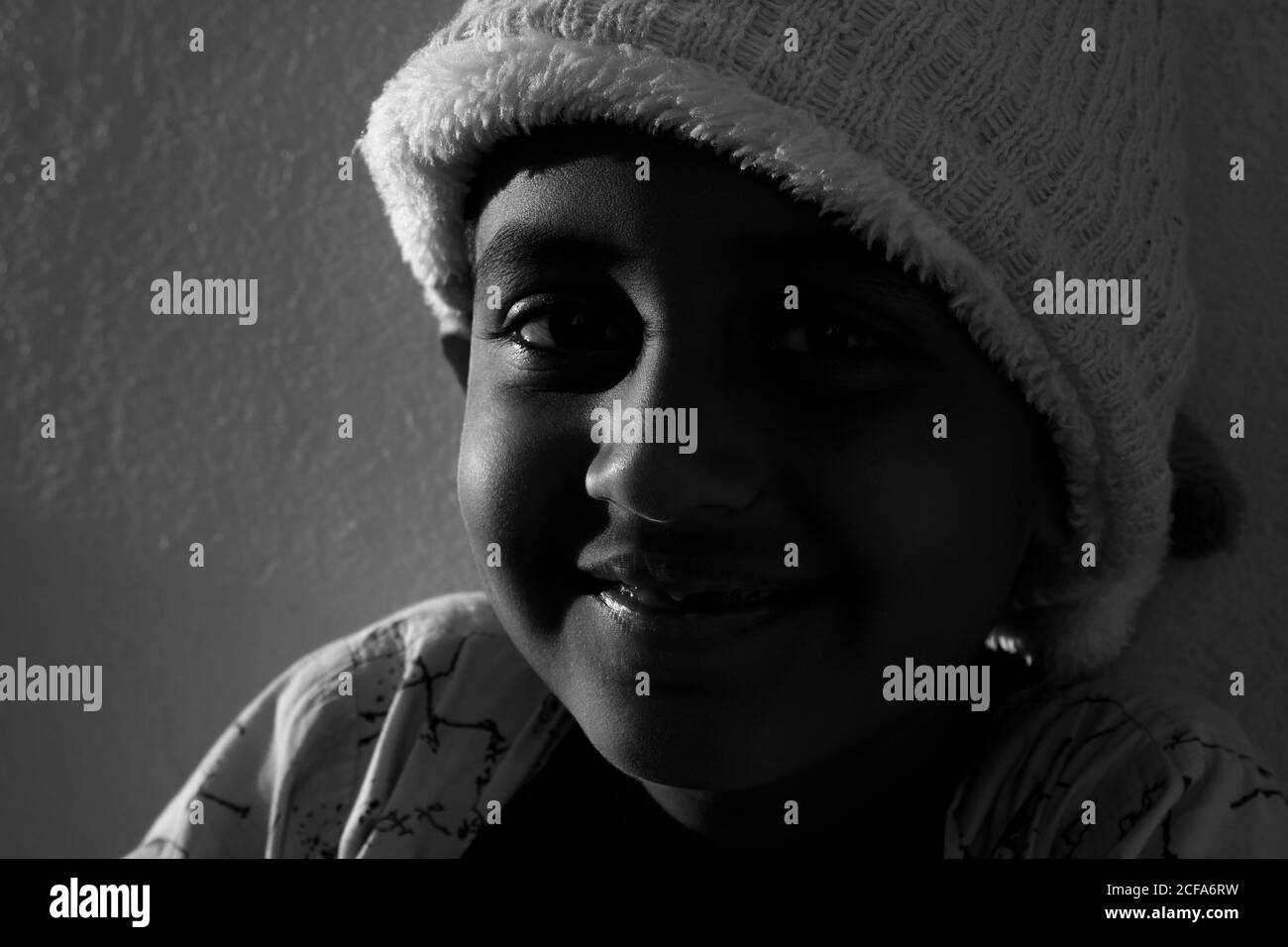 Un colpo closeup di ragazzo indiano sorridente in luce del tramonto foto in bianco e nero Foto Stock