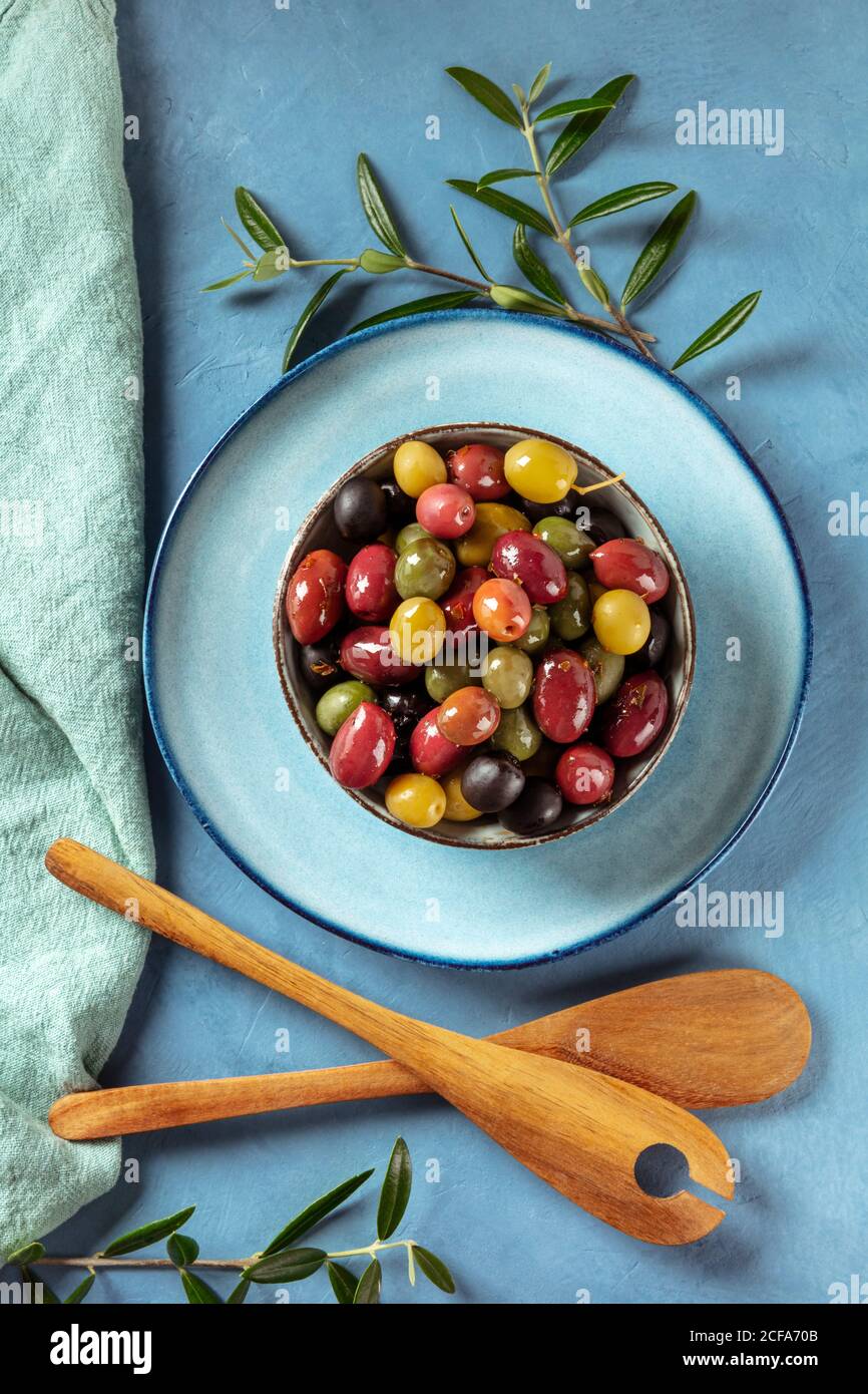 Olive. Una varietà di olive verdi, nere e rosse, con foglie e cucchiai di  legno, colpo dall'alto verso il basso Foto stock - Alamy