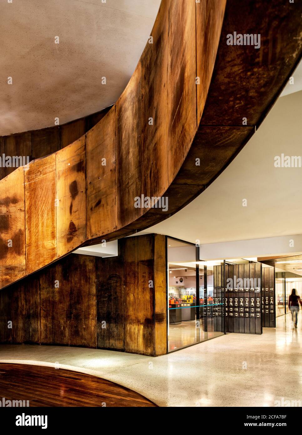 Ampio corridoio di un edificio d'uffici con metallo arrugginito e legno pannelli su pareti in composizione con pavimento in pietra lucida e. divisori in vetro in stile industriale Foto Stock