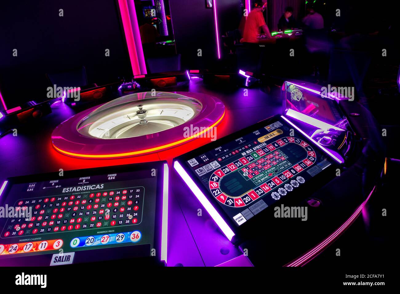 Tavolo da casinò con roulette moderna e schermi digitali illuminati da luci al neon nel casinò scuro Foto Stock