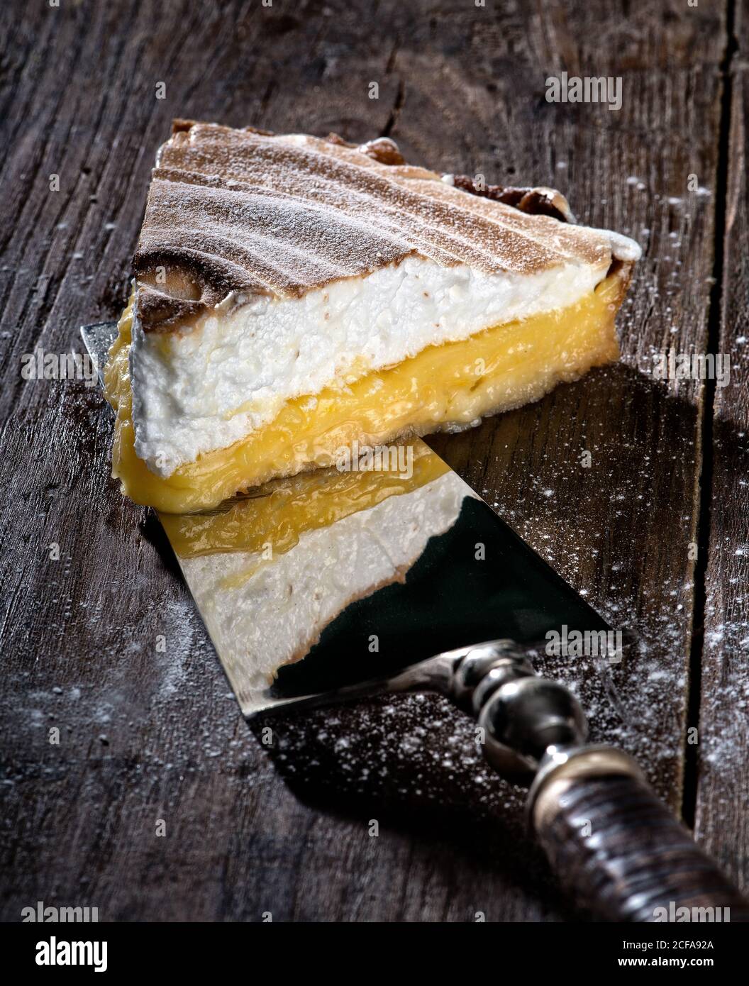 Server torta vintage con un pezzo di succosa torta al limone con strato di meringa marrone Foto Stock