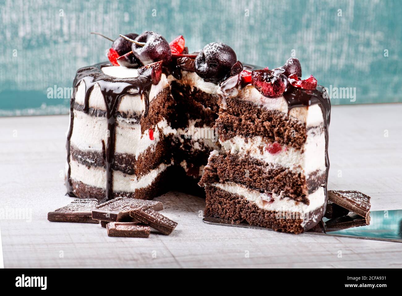 Torta della foresta nera con biscotti al cioccolato e crema con ciliegie posizionato su sfondo traballato Foto Stock