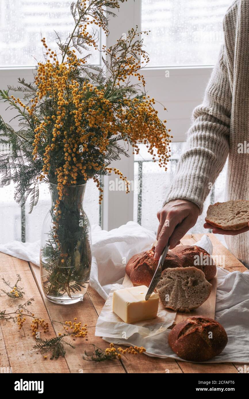 donna senza volto che sparge il burro sul pane in cucina Foto Stock