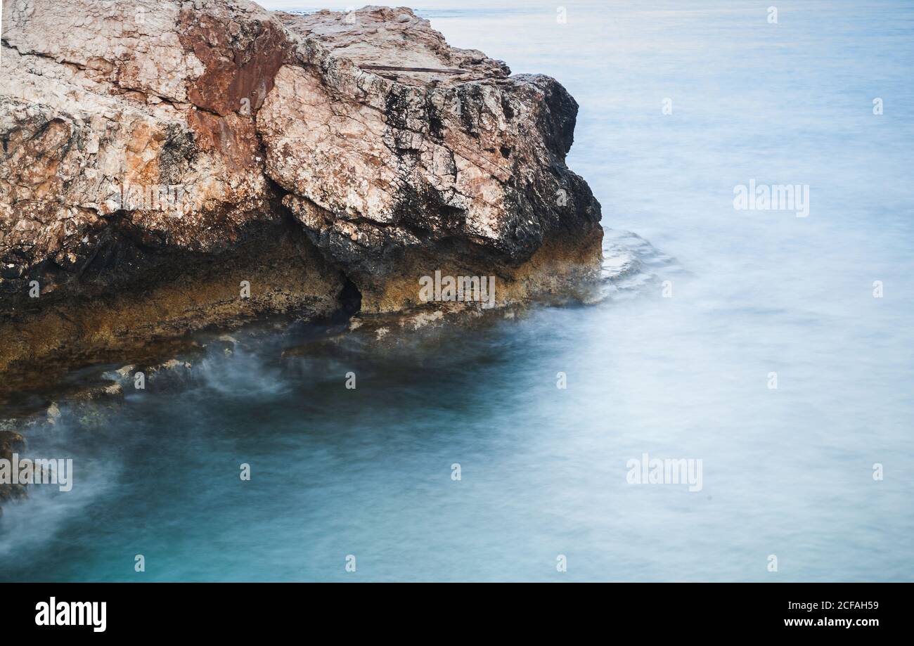 Costa del Mar Mediterraneo, paesaggio con rocce scure. Foto a lunga esposizione con effetto naturale dell'acqua sfocata. Ayia Napa, isola di Cipro Foto Stock
