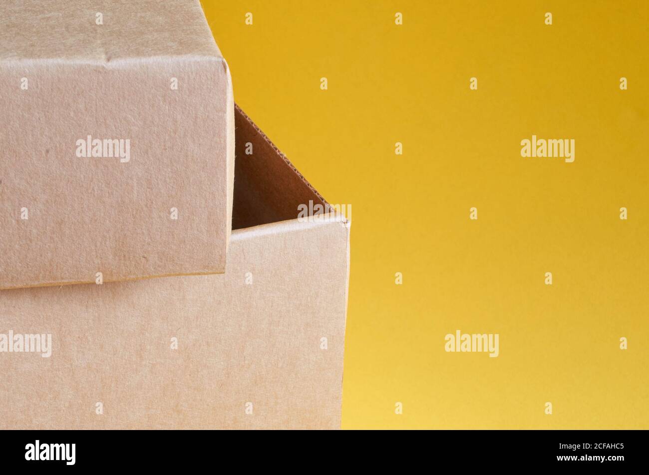 Angolo di una scatola di cartone marrone primo piano su un sfondo giallo Foto Stock