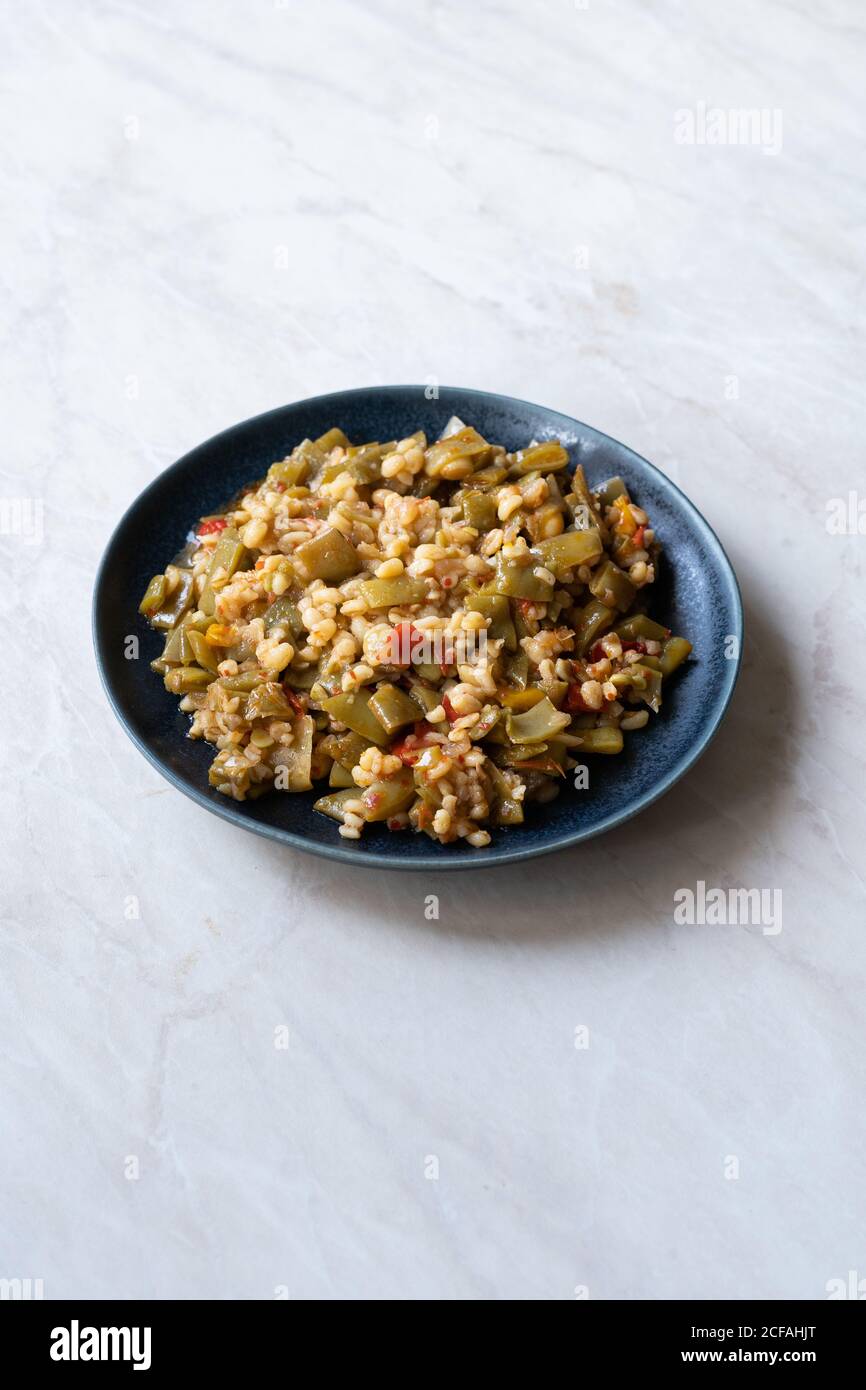 Olio di oliva turco cibo piselli verdi / Fasulye Diblesi o Ayse Kadin Dible con Bulgur / riso bulghur servito in piatto tradizionale sano cibo biologico. Foto Stock