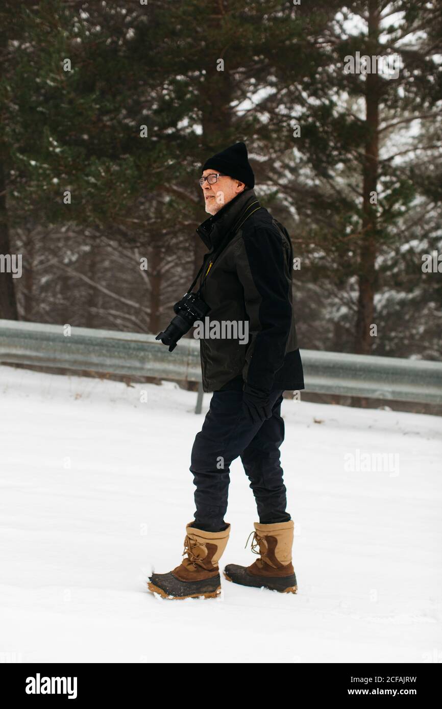 Uomo caucasico anziano che cammina sulla neve per prenderne foto di  paesaggi Foto stock - Alamy