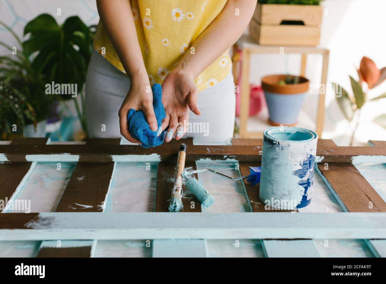 Una ragazza giovane sta pulendo la vernice dalle sue dita. Foto Stock