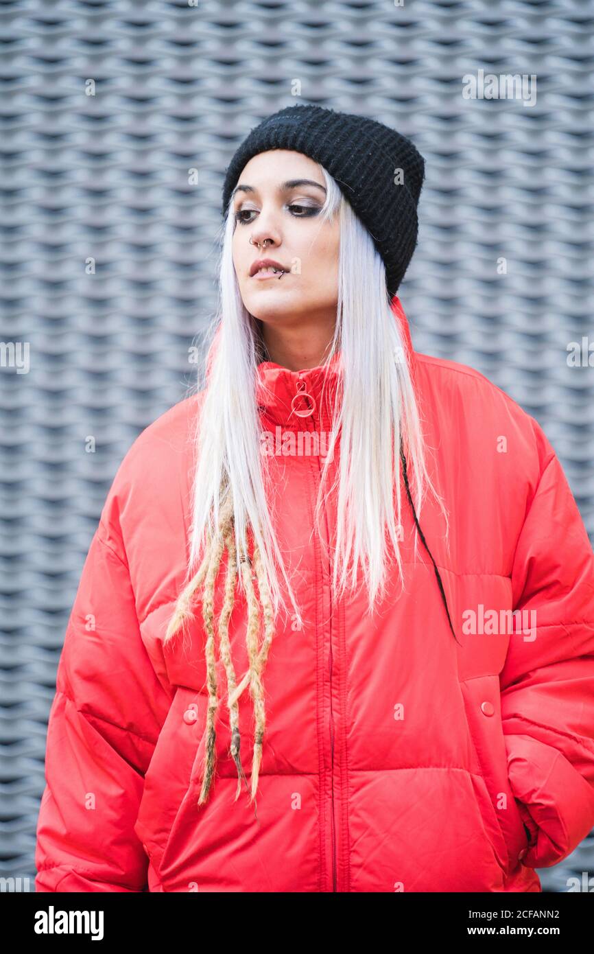 Donna bionda giovane hipster in elegante giacca rossa calda e. cappello in  piedi contro moderno sfondo di metallo parete Foto stock - Alamy