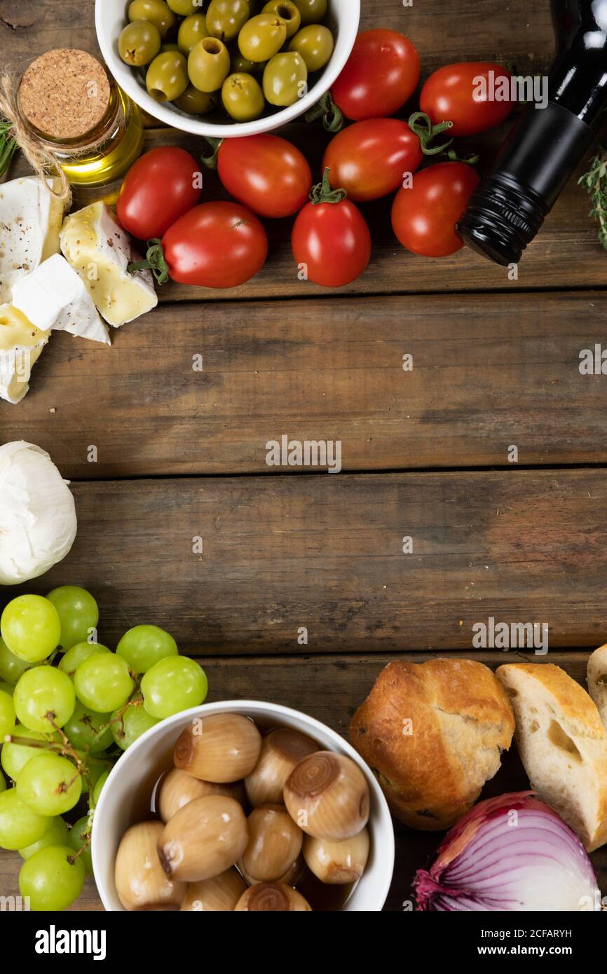Vista su un tagliere di legno con pane, formaggio, salsiccia, frutta e vino su una superficie di legno Foto Stock