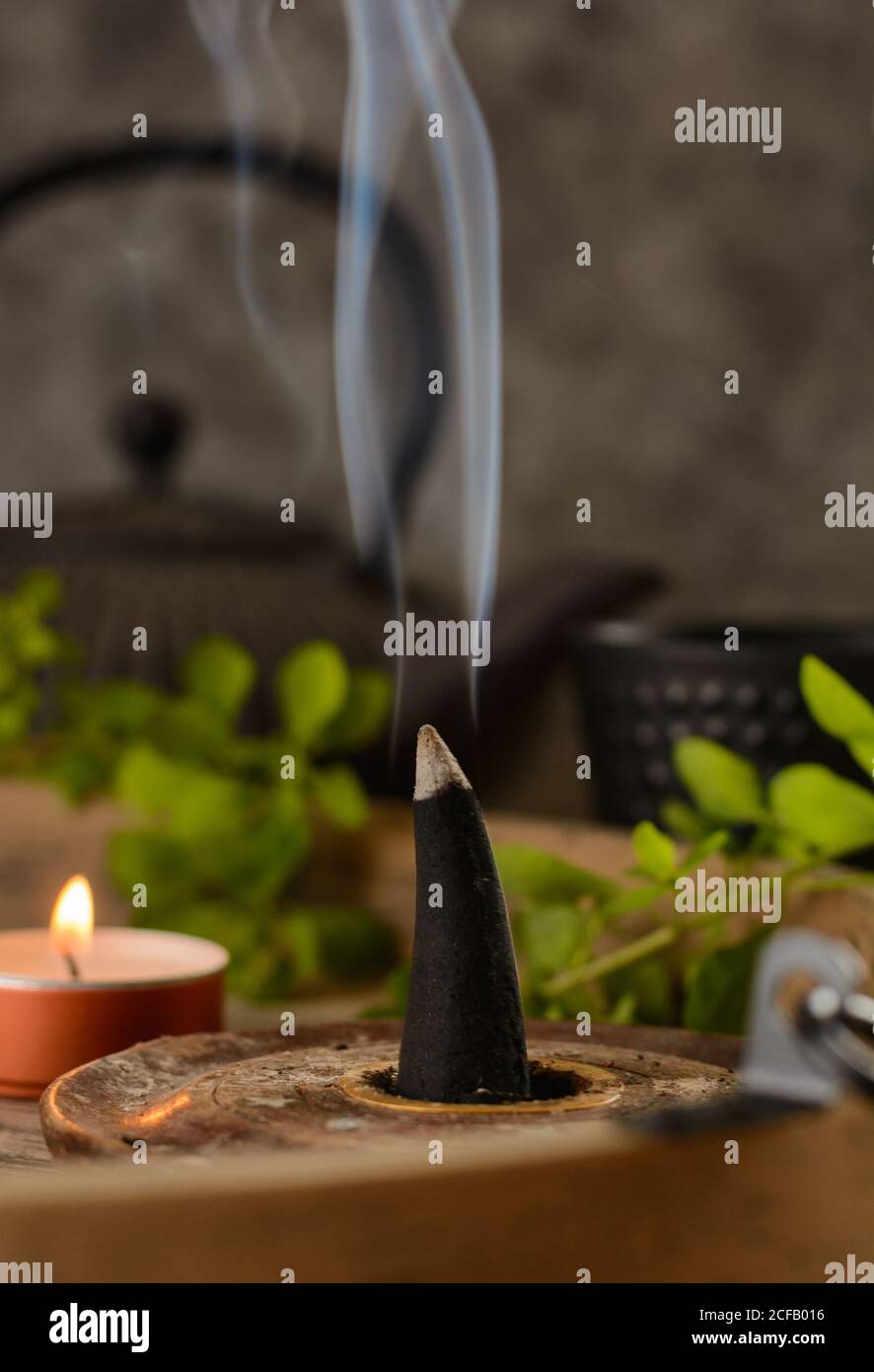 Composizione del cono di incenso e delle candele di tè bruciate su legno vassoio con teiera orientale preparato per il relax e la meditazione Foto Stock