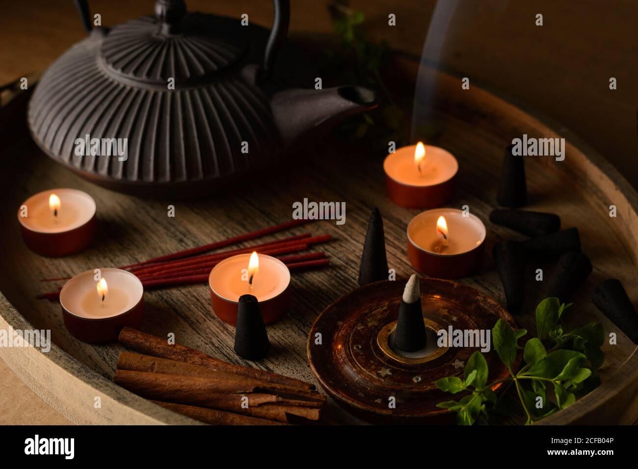 Composizione del cono di incenso e delle candele di tè bruciate su legno vassoio con teiera orientale preparato per il relax e la meditazione Foto Stock