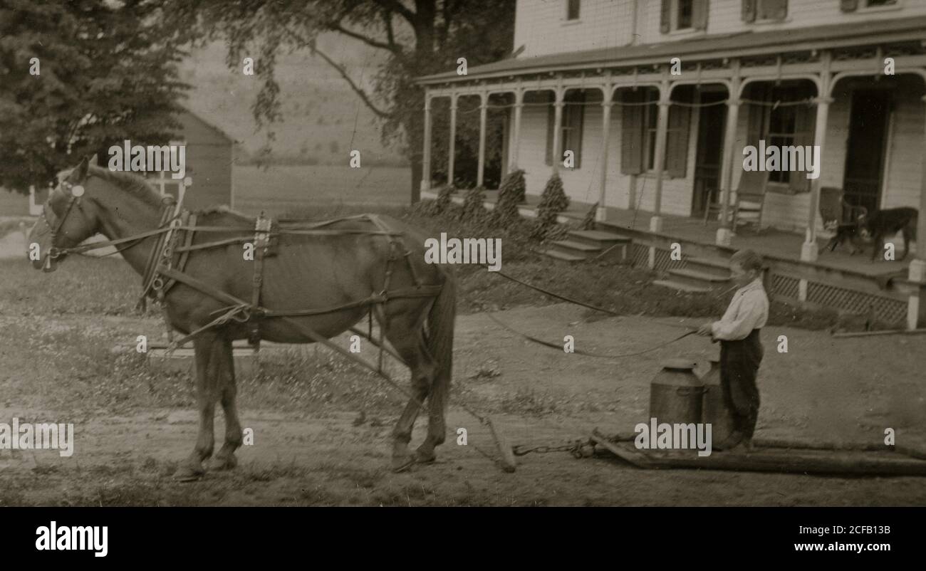 Otto anni di Jack trasporto di bombolette di latte sulla barca di pietra. Questo comporta alcuni il sollevamento di oggetti pesanti Foto Stock