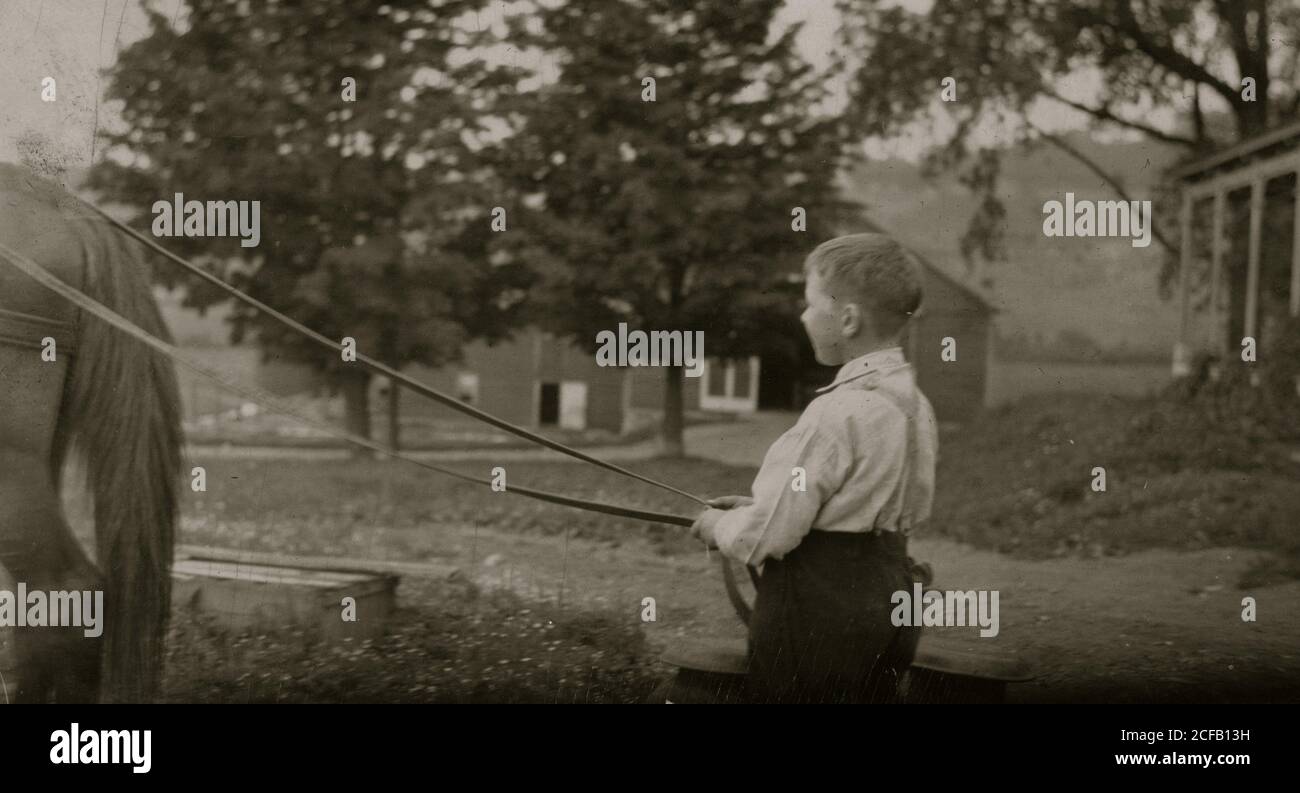 Otto anni di Jack trasporto di bombolette di latte sulla barca di pietra. Questo comporta alcuni il sollevamento di oggetti pesanti Foto Stock