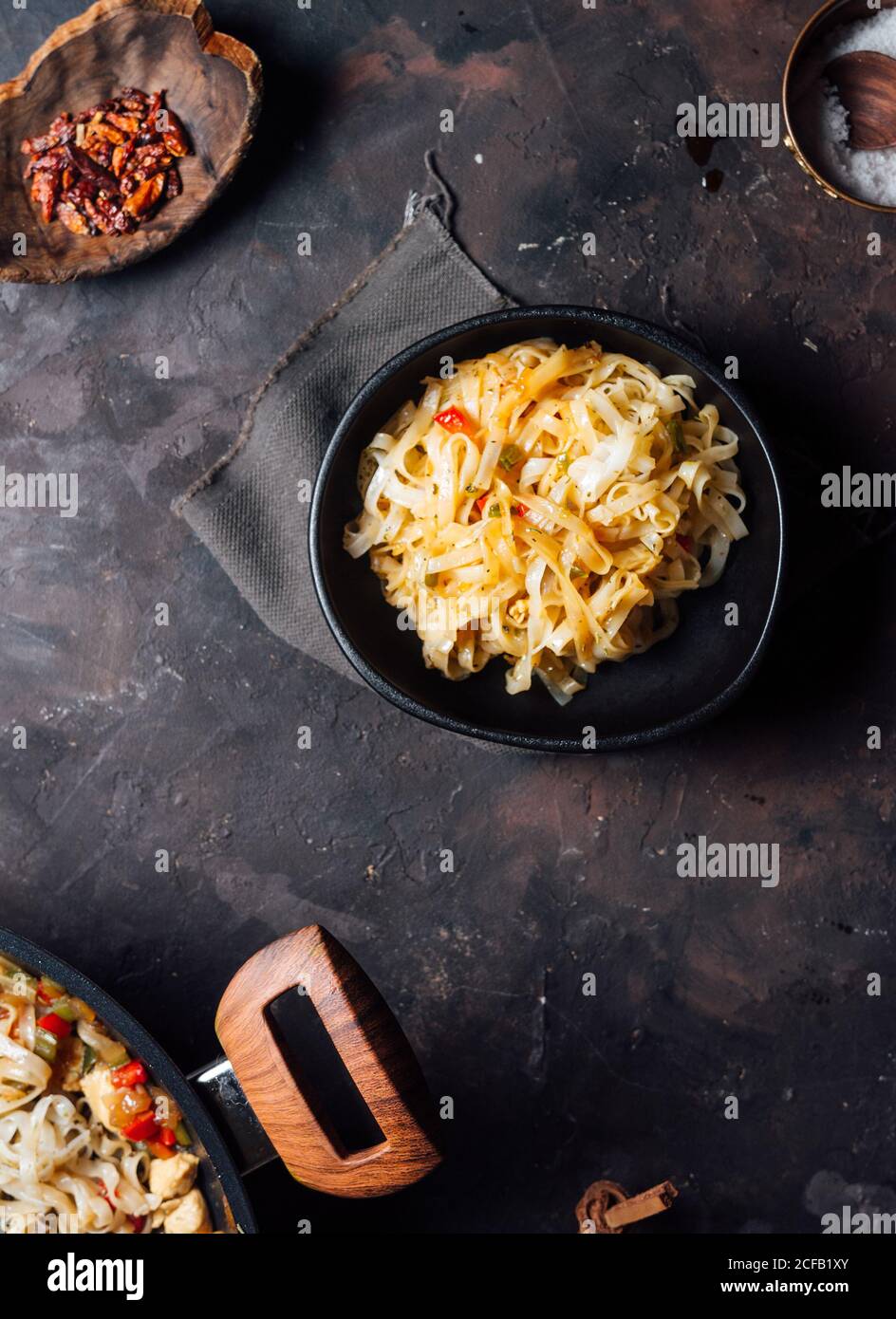 Vista dall'alto degli appetitosi spaghetti piccanti con pollo carne e verdure su padella posta su rustico scuro tabella Foto Stock