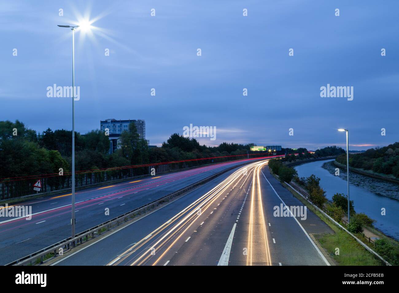 Percorsi leggeri di automobili che accelerano su un'autostrada britannica prima dawn Foto Stock