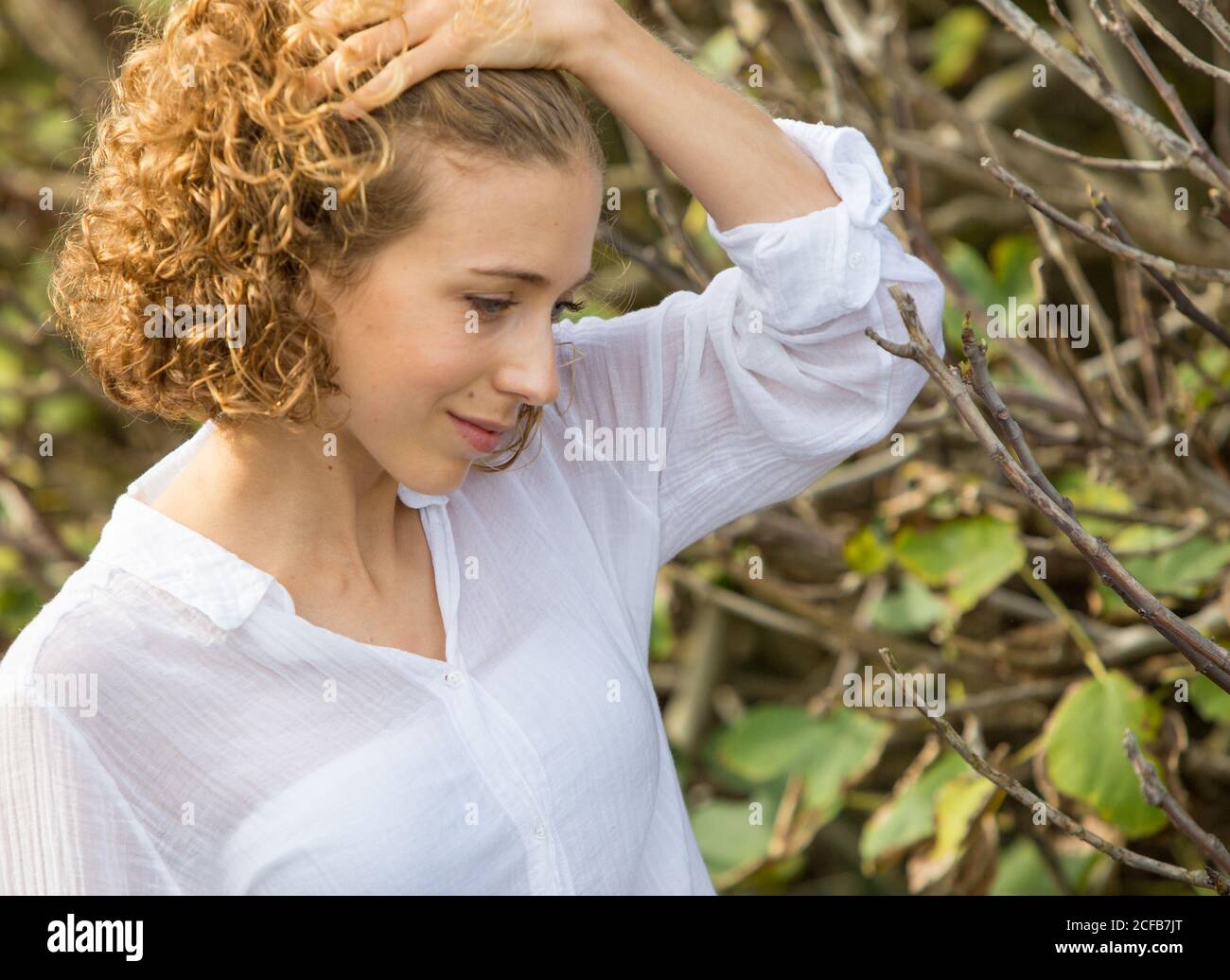 Giovane attraente affascinante Donna guardando rami secchi di arbusto su sfondo sfocato Foto Stock