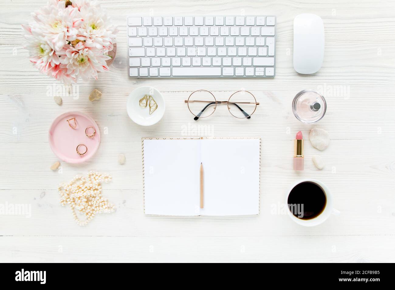 Spazio di lavoro con, computer, carta bianca, crisantemo. Accessori moda donna su sfondo bianco di legno. Riviste, media. Disposizione piatta, vista dall'alto Foto Stock
