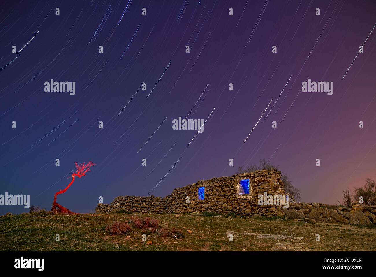 Lunga esposizione cielo stupefacente con stelle di sera e invecchiato costruzione di rocce in collina Foto Stock